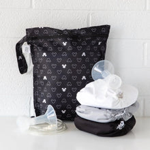 Load image into Gallery viewer, Bumkins Wet Bag: Mickey Mouse Icon Black + White sits against a white brick wall, with cloth diapers and breast pump parts in front.
