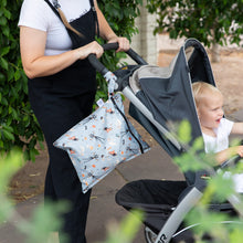 Load image into Gallery viewer, A person in black overalls pushes a stroller with a toddler while a Bumkins Wet Bag: No Tricks, Just Treats hangs from the handle.

