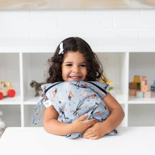 Load image into Gallery viewer, A child with curly hair hugs a Bumkins Wet Bag: No Tricks, Just Treats at a white table. Toys and blocks decorate the shelves behind.
