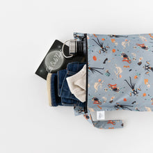 Load image into Gallery viewer, Bumkins Wet Bag: No Tricks, Just Treats holds a book, water bottle, blue jeans, and a light shirt on a white background.
