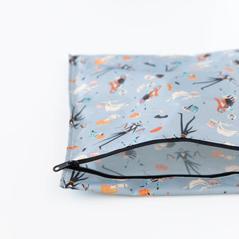 Bumkins Wet Bag: No Tricks, Just Treats lays unzipped on a white background, revealing its interior.