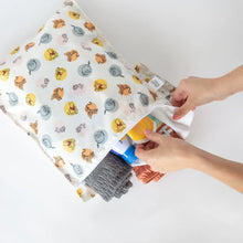 Load image into Gallery viewer, Hands organize beach gear like a towel, sunscreen, and swimsuit in a Bumkins Wet Bag: Winnie and Friends on a white background.
