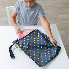 Load image into Gallery viewer, A child places a pink plate into a Bumkins Wet Bag: Super Mario™ Lineup at a white table.
