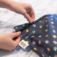 Load image into Gallery viewer, Close-up of hands zipping a Bumkins Wet Bag: Super Mario™ Lineup on a marble surface.
