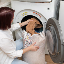 Load image into Gallery viewer, A person loading clothes into a front-loading washing machine from a Bumkins Extra Large Wet Bag: Wander.
