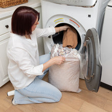 Load image into Gallery viewer, A person kneels by a front-loading washer, placing clothes inside from a Bumkins Extra Large Wet Bag: Wander, made of waterproof fabric.
