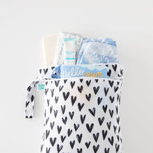 Load image into Gallery viewer, Bumkins Wet/Dry Bag: Hearts holds diapers, cream, and wipes on a white background.
