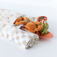 Load image into Gallery viewer, Bumkins Wet/Dry Bag: Palm Daze holds crab plush, baby clothes, a blanket, and sand toys on a white background.
