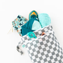Load image into Gallery viewer, Bumkins Wet/Dry Bag: Charcoal Check with swim trunks, a towel, goggles, shoes, and teal swimsuit on a white background.
