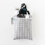 Bumkins Wet/Dry Bag: Lunar Phase holds gym essentials like a bottle, phone, towel, clothes and toiletries on a white background.
