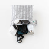 Bumkins Wet/Dry Bag: Lunar Phase lays on a white background, filled with gym essentials like clothes, a towel, a phone, and a water bottle.