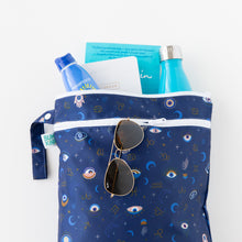 Load image into Gallery viewer, Bumkins Wet/Dry Bag: Evil Eye holds sunglasses, books, sunscreen, and a bottle on a white background.
