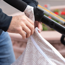 Load image into Gallery viewer, Close-up of a person attaching a Bumkins Wet/Dry Bag: Wander to a stroller handle outside.
