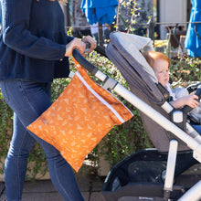 Load image into Gallery viewer, A woman pushes a stroller with a child outdoors; a Bumkins Wet/Dry Bag: Grounded hangs from the handle.
