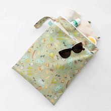 Load image into Gallery viewer, Bumkins Wet/Dry Bag: Camp Gear holds a beige towel, sunglasses, and sunscreen on a white background.
