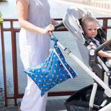 Load image into Gallery viewer, An adult pushes a stroller with a child near a waterfront with Bumkins Wet/Dry Bag: Mickey &amp; Friends Forever attached to the handle.
