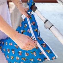 Load image into Gallery viewer, A person unzips a Bumkins Wet/Dry Bag: Mickey &amp; Friends Forever attached to a stroller handle.
