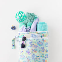 Load image into Gallery viewer, Bumkins Wet/Dry Bag: Aloha Stitch holds a pacifier, purple and teal outfit, a ball, shoes, teal towel, and sunglasses on a white background.
