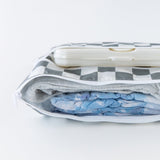 Bumkins Wet/Dry Clutch: Charcoal Check lays open on a  white background with diapers, clothes, and wipes inside.