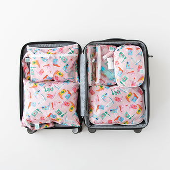 An open suitcase on a white background with Bumkins Wet/Dry Clutch: Boots inside next to other matching bags.