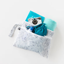 Load image into Gallery viewer, Roamio by Bumkins Wet/Dry Clutch: Disco Check holds a book, camera, towel, sunscreen, and swimsuit on a white background.
