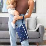 A woman holds child in a cozy living room with a Bumkins Wet/Dry Clutch: Evil Eye on her wrist.