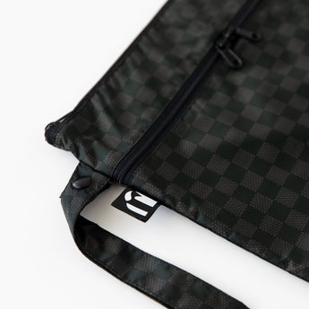 Close-up of Roamio by Bumkins Wet/Dry Clutch: Rich Black on a white background with focus on the side handle and logo tag.