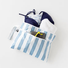Load image into Gallery viewer, Roamio by Bumkins Wet/Dry Clutch: Nautical Stripe holds a bikini, towel, sunglasses &amp; passport on a white background.
