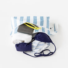Load image into Gallery viewer, Roamio by Bumkins Wet/Dry Clutch: Nautical Stripe lays open on a white background with a towel, swimsuit, passport, and sunglasses inside.
