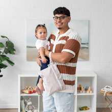 Load image into Gallery viewer, A man in a knit shirt holds a toddler and a Bumkins Wet/Dry Clutch: Wander amid toy shelves and a plant in the backdrop.
