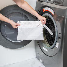 Load image into Gallery viewer, A person holds a Bumkins Wet/Dry Clutch: Wander in front of a front-loading washing machine.
