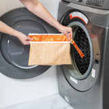 A person holds a Bumkins Wet/Dry Clutch: Grounded in front of a a front-loading washer.