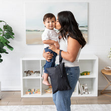Load image into Gallery viewer, A woman kisses a child in a modern living room with a Bumkins Wet/Dry Clutch: Black on her arm.
