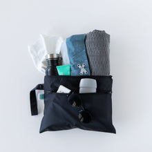 Load image into Gallery viewer, Bumkins Wet/Dry Clutch: Black holds a water bottle, blue clothes, gray towel, toiletries, sunglasses, and deodorant on a white background.
