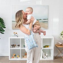Load image into Gallery viewer, A joyful woman holds a laughing baby in a bright room, with a Bumkins Wet/Dry Clutch: Mickey + Minnie Sunny Side Up on her arm.
