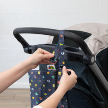 Load image into Gallery viewer, A person attaches a Bumkins Wet/Dry Clutch: Super Mario™ Lineup to a stroller using the snap handle.
