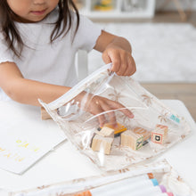 Load image into Gallery viewer, A child places wooden blocks into a Bumkins Clear Travel Bag 3 Pack: Palm Daze, with paper and markers nearby on a white table.
