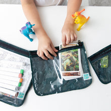 Load image into Gallery viewer, A child puts a card into a Bumkins Clear Travel Bag 3 Pack: Starry Cactus, surrounded by dinosaur toys and art supplies on a white table.
