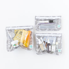 Load image into Gallery viewer, Three clear travel bags from Bumkins Clear Travel Bag 3 Pack: Lunar Phase, filled with skincare products on a white background.
