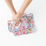 A person uses a wipe to clean the inside of Bumkins: Clear Travel Bag 3 Pack: Boots on a white table.