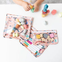 Load image into Gallery viewer, A child plays with blocks on a white table near Bumkins Clear Travel Bag 3 Pack: Yoga Pals filled with toys, markers, and stamps.
