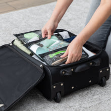 Load image into Gallery viewer, A person packs Bumkins Clear Travel Bag 3 Pack: Rich Black filled with toiletries into an open black suitcase on a gray rug.
