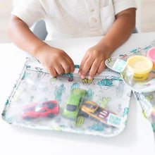 Load image into Gallery viewer, A child zips a Bumkins Clear Travel Bag 3-Pack: Cacti filled with toy cars on a white table.
