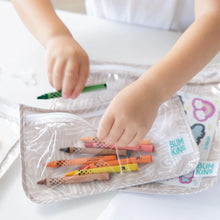 Load image into Gallery viewer, Close-up of a child placing a green crayon in a Bumkins Clear Travel Bag 3-Pack: Wander at a white table.
