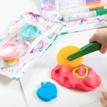 Load image into Gallery viewer, Close-up of a child playing with a yellow rolling cutter on pink clay near Bumkins Clear Travel Bag 3-Pack: Watercolor with art supplies.
