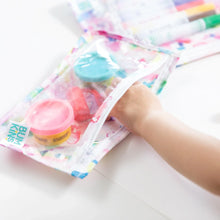 Load image into Gallery viewer, Close-up of a child grabbing colorful modeling clay from a Bumkins Clear Travel Bag 3-Pack: Watercolor at a white table.
