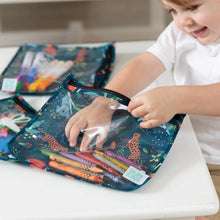 Load image into Gallery viewer, A child smiles while organizing markers in Bumkins Clear Travel Bag 3-Pack: Jungle on a white table.
