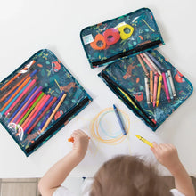 Load image into Gallery viewer, A child draws with crayons at a table, surrounded by Bumkins Clear Travel Bag 3-Pack: Jungle filled with pens, crayons, and art supplies.
