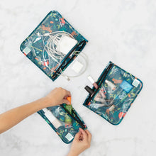 Load image into Gallery viewer, Hands organize makeup and electronics in Bumkins Clear Travel Bag 3-Pack: Jungle on a white background.
