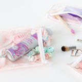 Close-up of Bumkins Clear Travel Bag 3-Pack: Lace on a white background with hair accessories and makeup inside.
